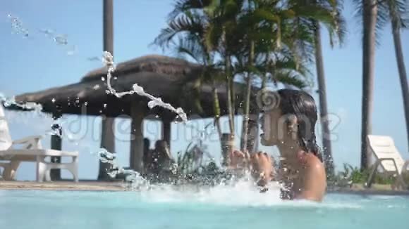 年轻漂亮的女人在游泳池里放松泳池瀑布下的女人慢动作1920x1080高清视频的预览图