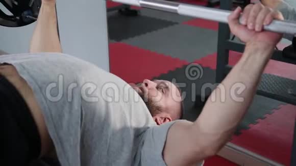 英俊的运动员在健身房的长凳上表演长凳按压视频的预览图