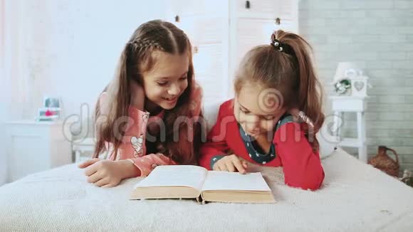 两个小朋友穿着睡衣他们在看书他们谈论和讨论这本书视频的预览图