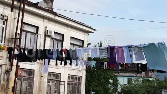 大量洗过的衣服挂在绳子上在房子附近的街道上干涸视频的预览图