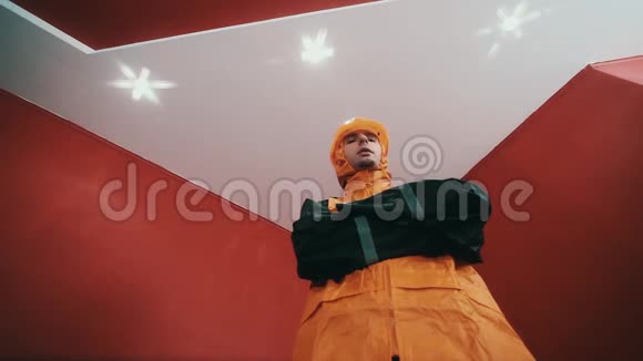 穿着建筑夹克和橙色安全帽的男人在红色的房间里手持武器一边说着视频的预览图