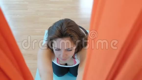 一个女人在瑜伽的橙色吊床上伸展脊柱视频的预览图