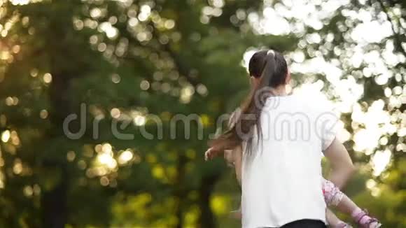 快乐的家庭在夏天的公园玩耍妈妈在花园里旋转着小女儿孩子们的笑声视频的预览图