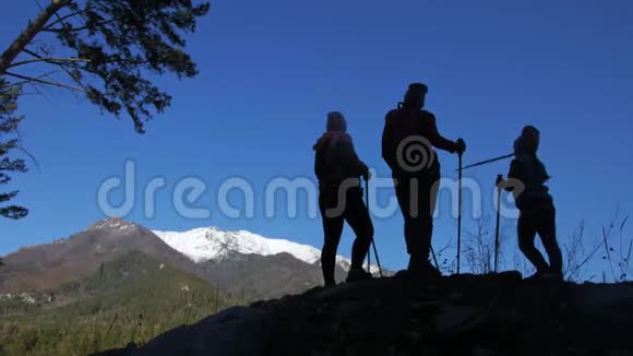 女人在山上行走在大自然中剪影女孩和孩子使用跋涉棒和北欧杆视频的预览图