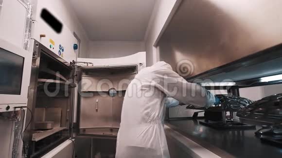 穿长袍和橡胶手套的科学家在实验室里把金属元素放进烤箱视频的预览图