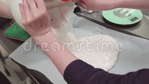 女人的手把奶油面团洒在烤盘上上面覆盖着烹饪纸视频的预览图