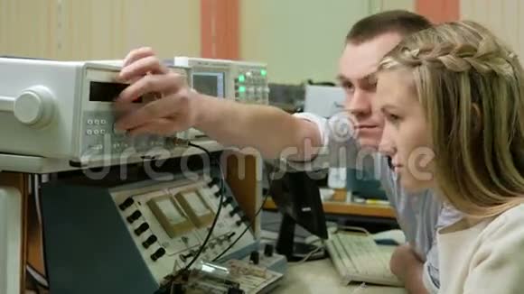 年轻的女工程师学生在实验室里和一个男人一起工作带着一台电气测量设备他们小心翼翼视频的预览图