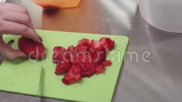 女人的手在金属桌上的厨房的砧板上叼着草莓视频的预览图