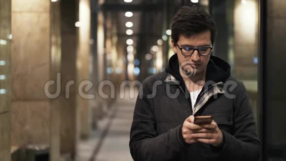 戴眼镜的年轻人晚上在街上发短信视频的预览图