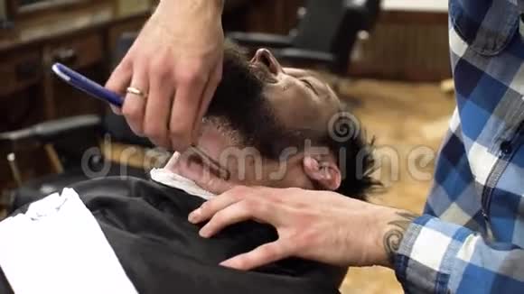 理发店刮胡子的人关门了专业理发师使用带锋利刀片和奶油凝胶的直剃刀视频的预览图