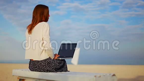 女性等待在蓝天下笔记本电脑上下载文件视频的预览图