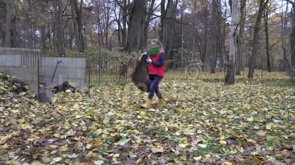 女人在后院工作秋季干叶堆肥堆4K视频的预览图