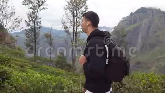 青年游客背着背包在山间小径散步背景是美丽的自然景观男性徒步旅行者视频的预览图