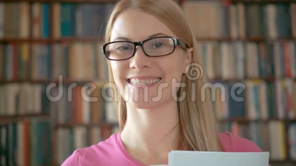 戴眼镜的学生站在图书馆的肖像背景书架视频的预览图