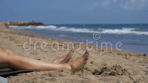 女人的腿慢慢地躺在海边的海滩上视频的预览图