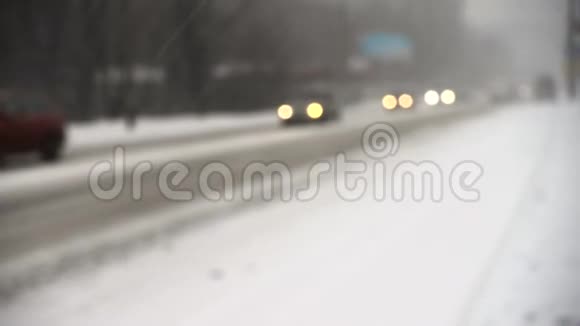 冬天白雪皑皑的街道上灯火通明的汽车视频的预览图