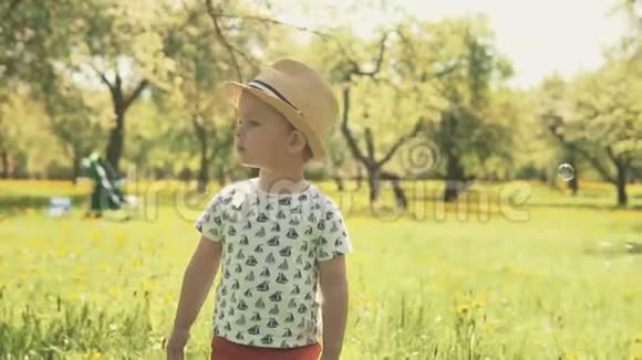 戴帽子的小男孩穿过泡泡小孩子在公园玩耍视频的预览图