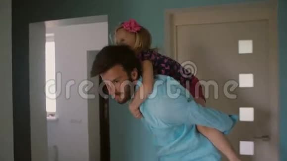 年轻的父亲背着他可爱的小女儿在房子里跳来跳去慢点斯泰迪达姆视频的预览图