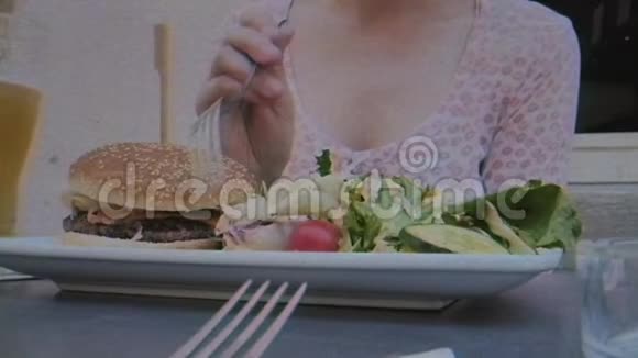 女人吃美味的汉堡和沙拉视频的预览图