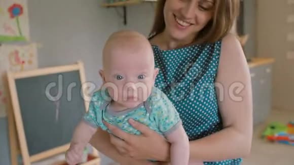 一个蓝色眼睛的婴儿的脸他的母亲抱着他看着相机慢点斯泰迪达姆视频的预览图