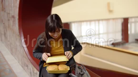 年轻女子在室内吃汉堡包视频的预览图