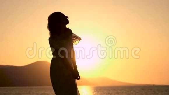 年轻漂亮的女人正在海边的夕阳下跳舞视频的预览图