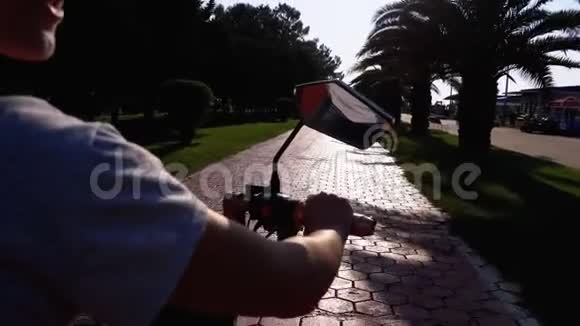 在度假小镇的红自行车道上女人骑着电动自行车骑着棕榈树视频的预览图