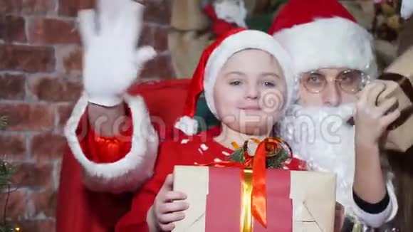 特写快乐的孩子们手里拿着礼物和圣诞老人一起挥手视频的预览图