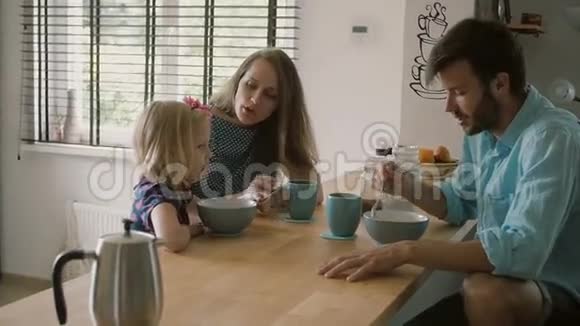 母亲在厨房的餐桌上和丈夫交谈时正对着女儿微笑慢点斯泰迪达姆视频的预览图