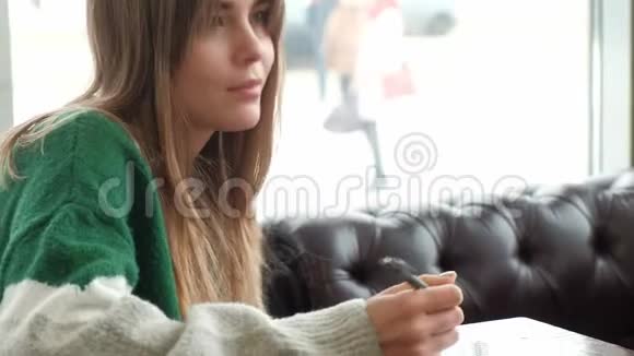在繁忙的咖啡店里一个女人坐着写日记视频的预览图