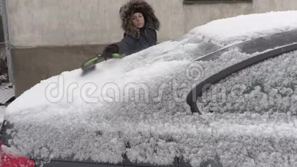 在雪地里用刷子靠近汽车的女人视频的预览图