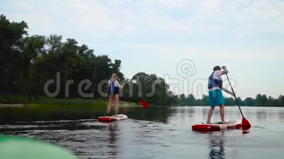 这对年轻夫妇正沿着河浮在皮划艇上视频的预览图