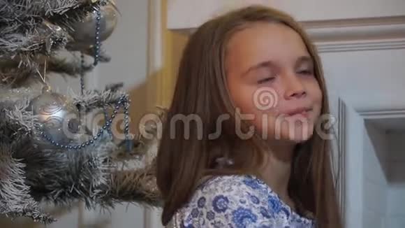 特写镜头女孩在壁炉和圣诞树旁打着哈欠伸展身体视频的预览图