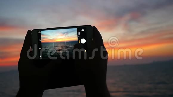 特写女性手拍一张美丽的日落海滩照片手机改变焦点到大海视频的预览图