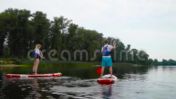 这对年轻夫妇正沿着河浮在皮划艇上视频的预览图