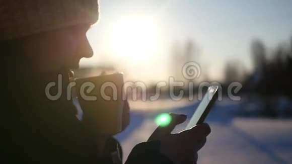 夕阳西下美丽的女孩喝着一杯热咖啡站在街上手里拿着电话视频的预览图