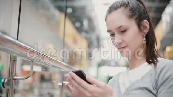 一个戴着漂亮耳环和马尾辫的女孩坐在公共场所在她的手机上打字视频的预览图