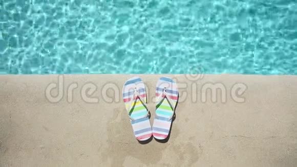蓝色游泳池附近的彩色夏季凉鞋视频的预览图