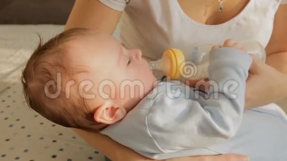 特写镜头可爱的小男孩躺在妈妈的手上吃着瓶子里的牛奶视频的预览图