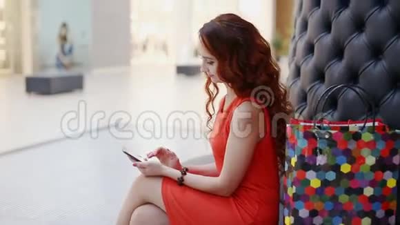 快乐的年轻女子使用智能手机购物中心视频的预览图