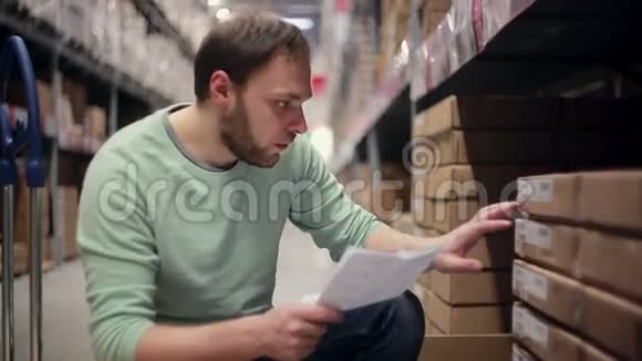 一个男人正在寻找必要的包裹把它们从货架上拿出来放在仓库里的纸板箱里视频的预览图