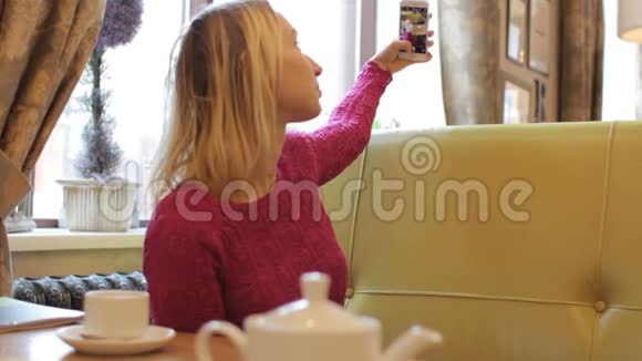 小美女在咖啡馆里用手机自拍视频的预览图