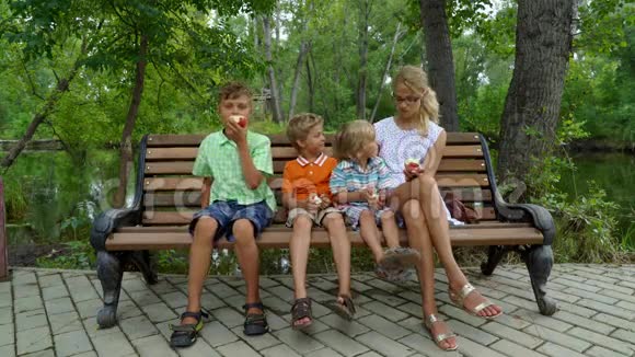 孩子们和妈妈坐在长凳上吃苹果视频的预览图