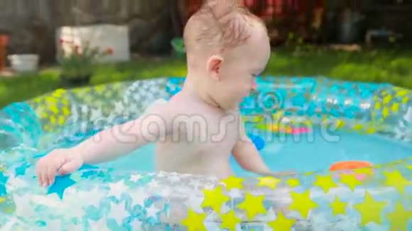 快乐的小男孩在后院草地上的充气游泳池里玩玩具视频的预览图