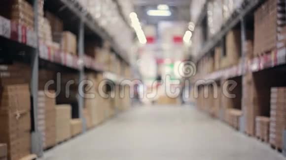 一名男子正推着一辆装满箱子的手推车在一个仓库里的装有纸板箱的调色板之间视频的预览图