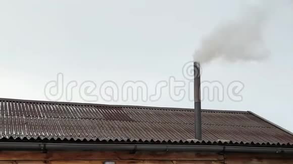 烟来自房子的烟囱屋顶上的管子有烟囱的房子在蓝天上抽烟视频的预览图