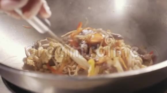 厨师在炒锅里用肉和蔬菜烹制面条视频的预览图