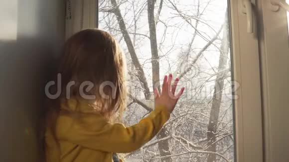 在白雪覆盖的树木背景下婴儿坐在窗台上玩耍视频的预览图