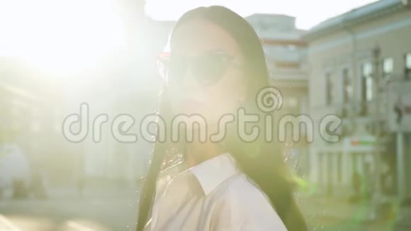 穿着白色衬衫的时髦深色头发在早晨的阳光下拍照视频的预览图