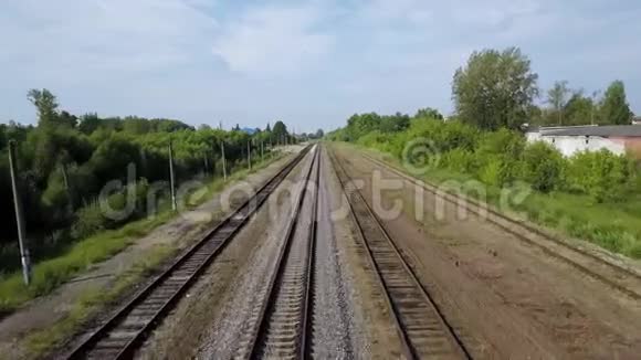 沿着灌木丛和树木的绿线铺成的一排排长长的铁路视频的预览图
